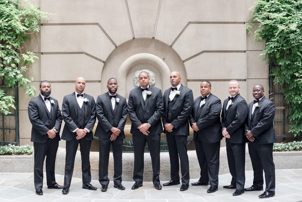 Groom and groomsmen standing and posing in courtyard of DC hotel