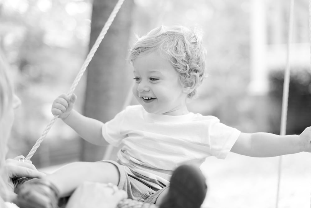 Candid photo of little boy playing on swing at home