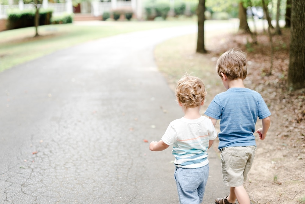 Boys walking together holding hands down VA driveway