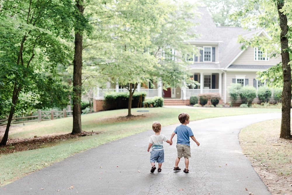 Brothers holding hands and walking down driveway in VA
