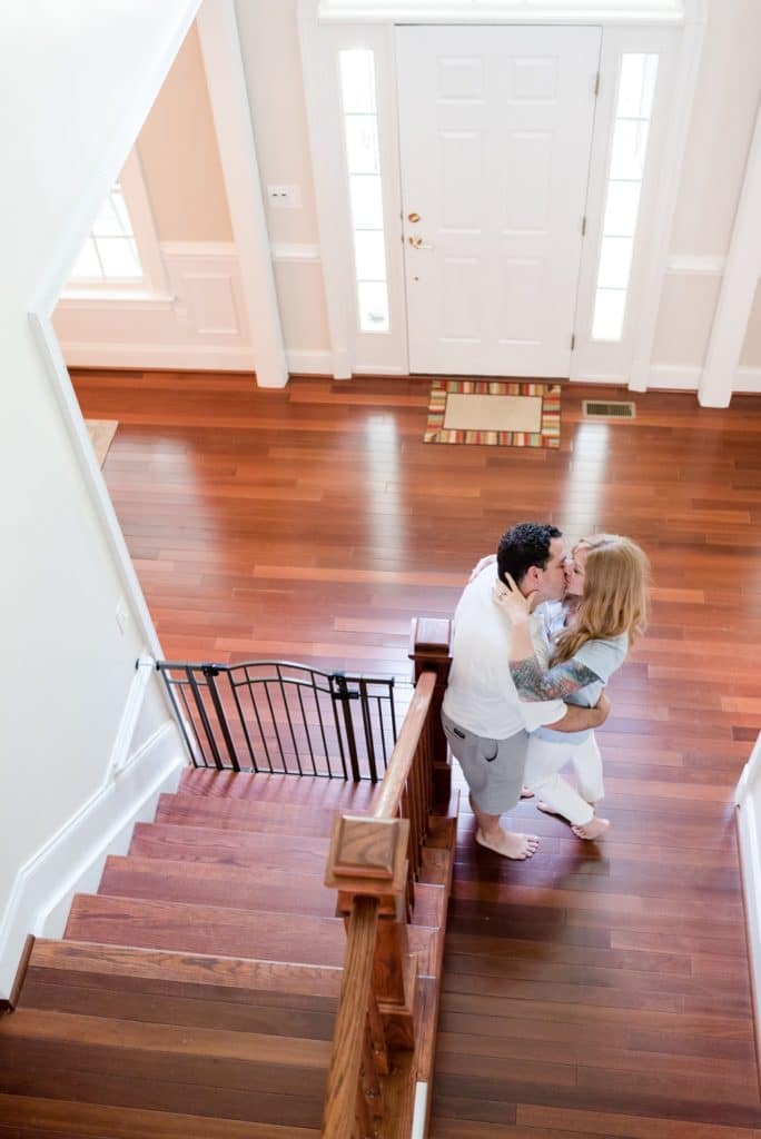 Parents kissing at bottom of stairs in their home