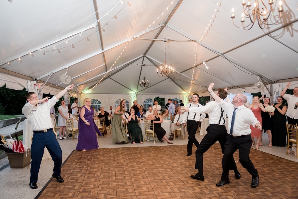 Groom garter toss at wedding reception at Rust Manor House tent