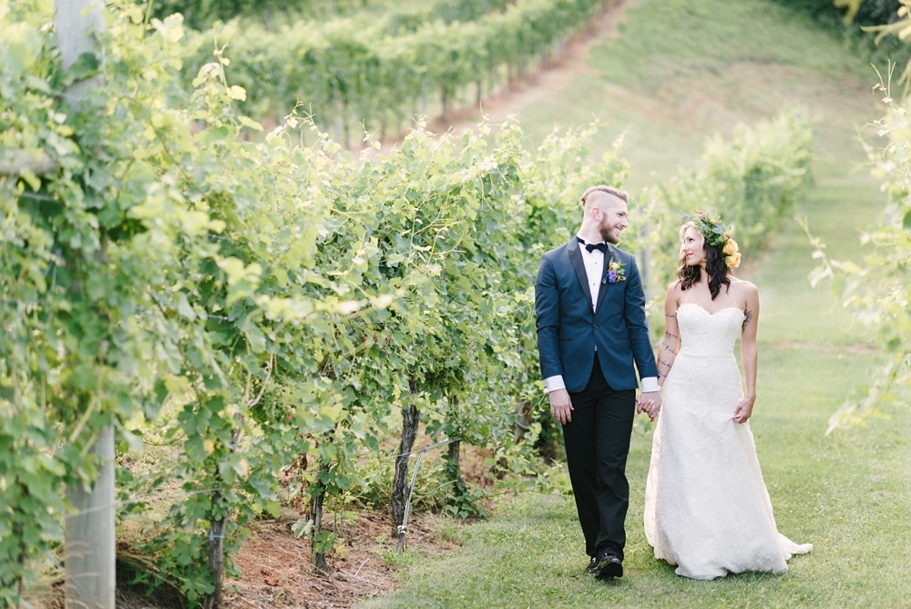 Bride and Groom walking together in vines at DelFosse Vineyards and Winery