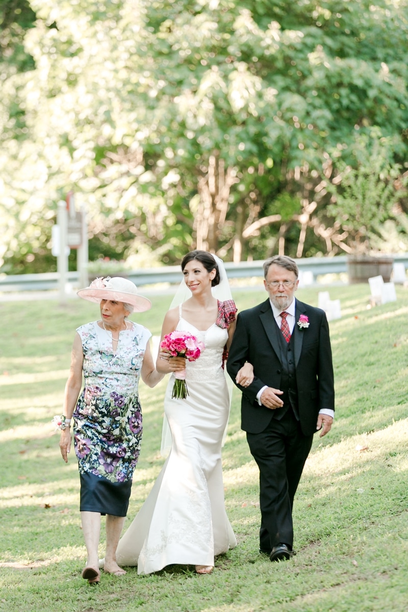 Bride and her mom and dad walking her down the aisle at Bowman Distillery