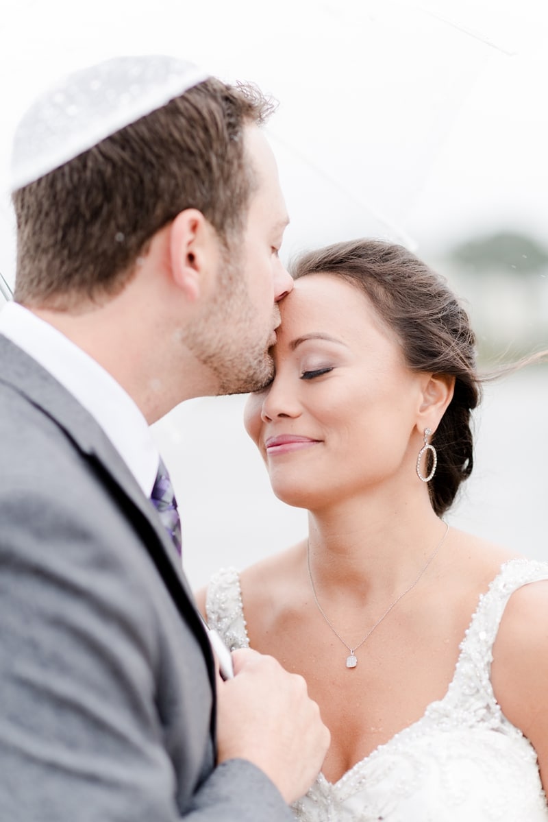 Groom kissing bride on forehead during their wedding day portraits together