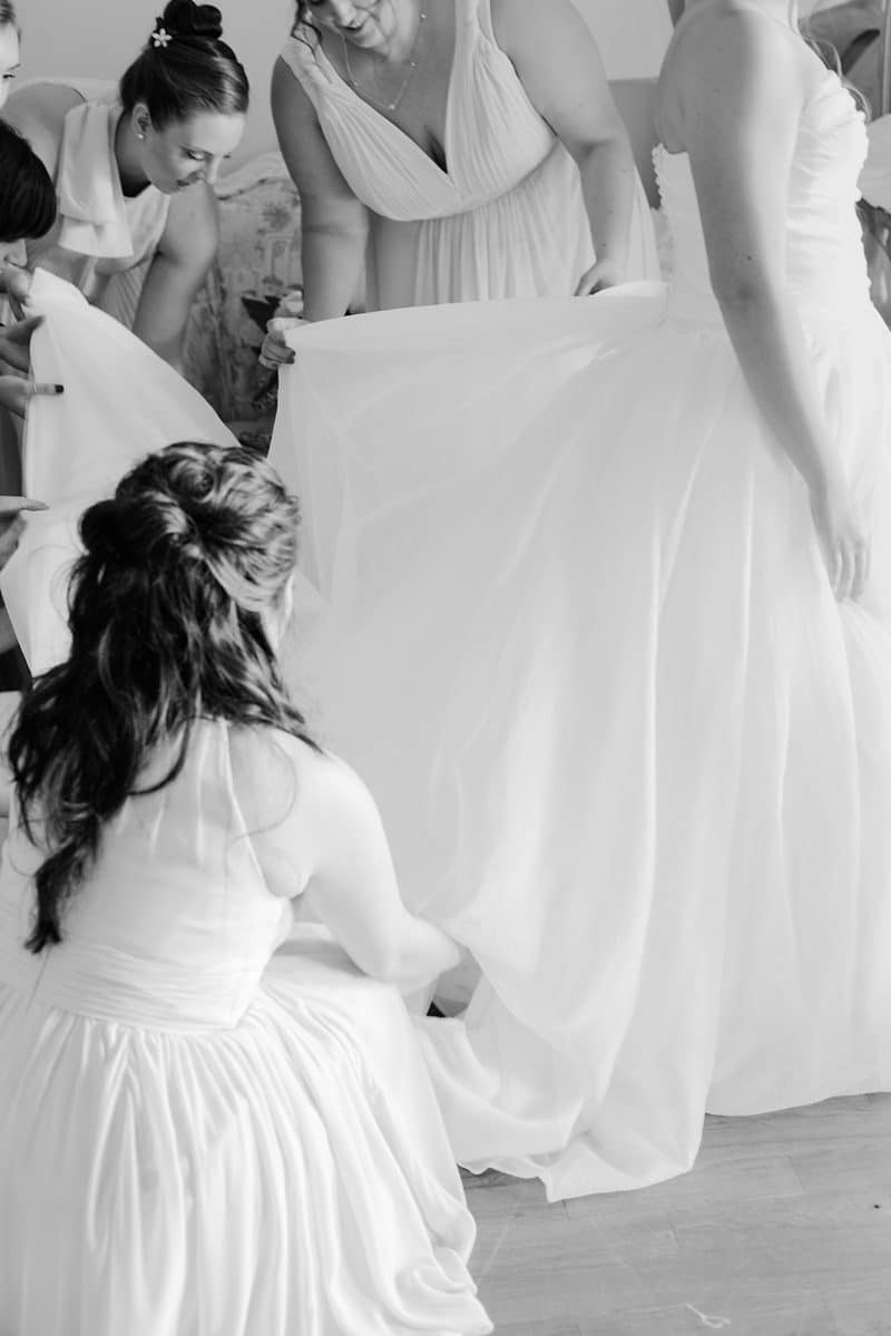 Bridesmaids helping bride get into her dress