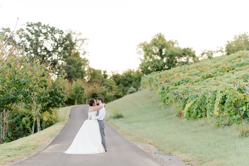 Bride and groom kissing each other by vines in Bluemont Vineyards