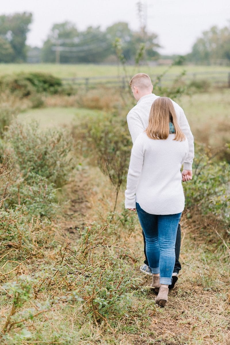 Engaged couple walking in field during engagement session