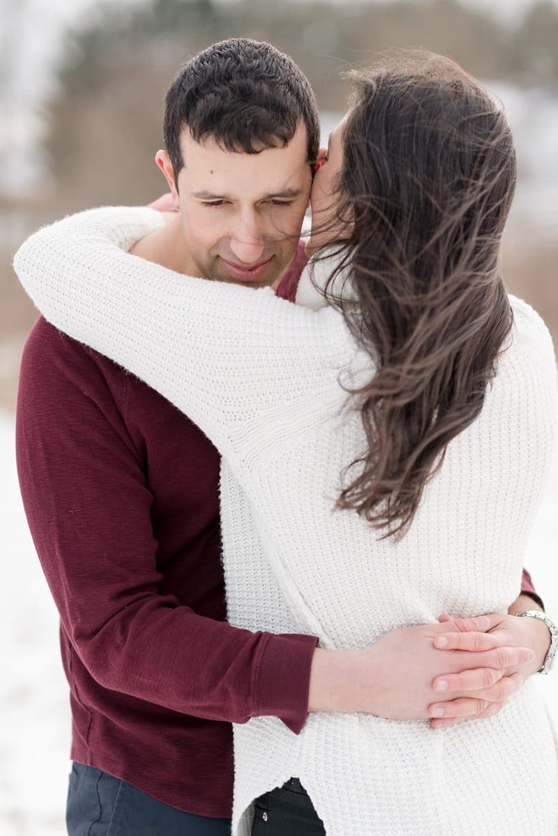couple holds each other during engagement session in the snow